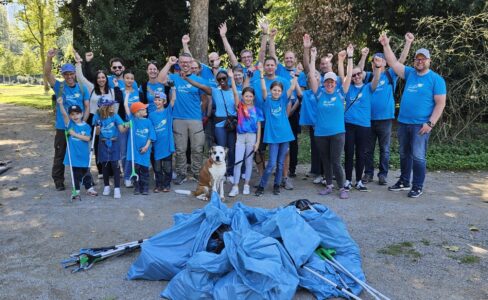 Das Team zusammengemischt aus den Bereichen interner Service, dem Einkauf und TRS der Targobank wurde durch Kinder von den Kolleg*innen unterstützt und steht im Düsseldorfer Hofgarten vor einem Haufen Müllsäcken und alle heben die Hände.