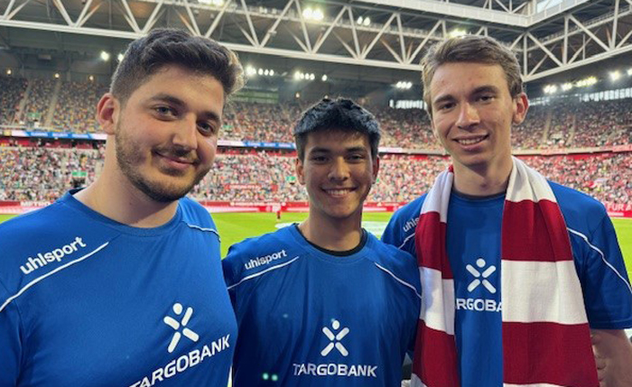 Drei Spieler der TARGOBANK Fußballmannschaft stehen in dem Fortuna Fußballstadion und lächeln in die Kamera.