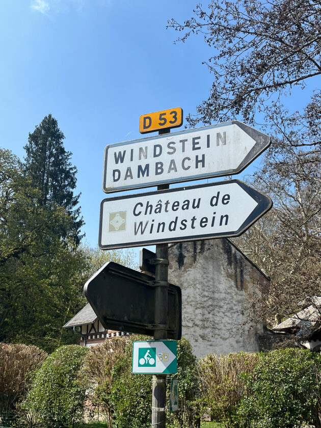 Ein Ortschild von Windstein/Dambach und Chateau de Windstein.