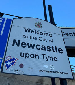 Willkommen in der Stadt Newcastle upon Tyne. Das Schild zeigt die Website newcastle.gov.uk und beinhaltet einige Aufkleber.