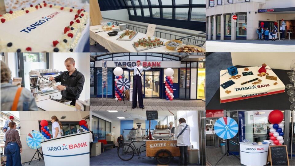 Das Bild zeigt eine Eröffnungsfeier der TARGOBANK mit einer Torte, Snacks und Getränken. Ein Barista bereitet Kaffee vor. Vor der Bank stehen ein Glücksrad und ein Stelzenläufer. Im Vordergrund sind Dekorationen mit roten und blauen Ballons sowie ein Informationsstand sichtbar.