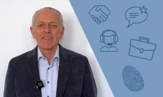 Ein Mann mit grauen Haaren, der ein graues Sakko und ein helles Hemd trägt, steht vor einem weißen Hintergrund. Er lächelt. Auf der rechten Seite des Bildes sind Icons, die eine Handshake, ein Sprechblasen-Symbol, einen Kopfhörer, eine Aktentasche und einen Fingerabdruck darstellen.