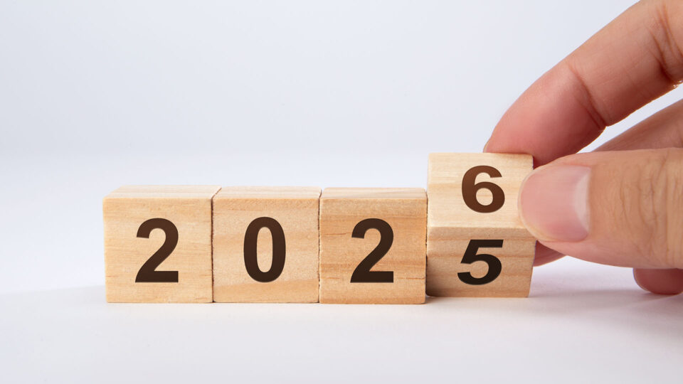 Ein Mensch hält einen Holzblock mit der Zahl 6, während die Zahl 5 links davon und die Zahlen 2, 0, 2 auf den anderen Blöcken sichtbar sind, die zusammen die Jahreszahl 2025 bilden.