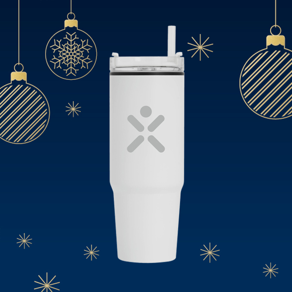 Ein weißer Getränkebecher mit einem durchsichtigen Deckel und Strohhalm, umgeben von Weihnachtsornamenten und einem blauen Hintergrund.