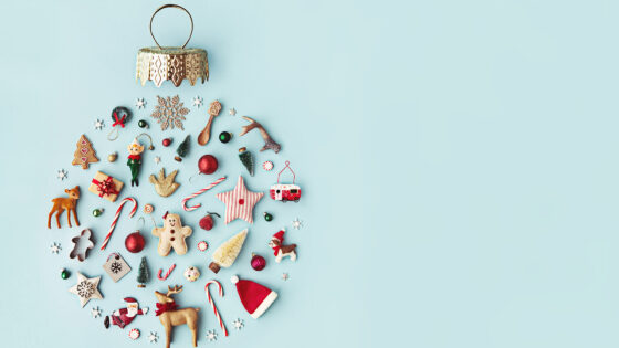 Eine Sammlung von Weihnachtsdekorationen und -figuren auf einem hellblauen Hintergrund, darunter Plätzchen, Figuren, Christbaumkugeln und kleine Weihnachtsbäume.