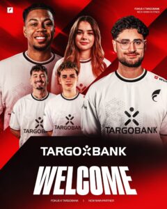 Ein Team von fünf Personen, die weiße T-Shirts mit dem Logo von TARGOBANK tragen, steht vor einem roten Hintergrund. Der Text "WELCOME" ist prominent in Weiß zu sehen, darunter steht "FOKUS X TARGOBANK | NEW MAIN PARTNER".