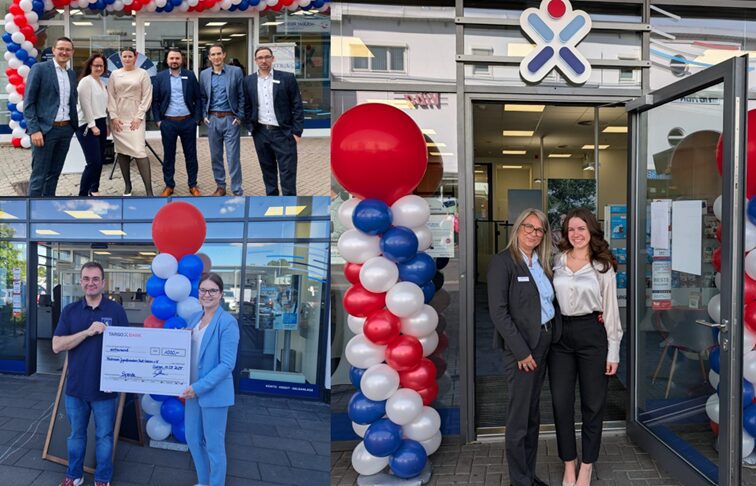 Das Bild zeigt eine Eröffnungsfeier mit einer Gruppe von Menschen vor einem Geschäft. Es gibt eine große bunte Ballon-Dekoration in Rot, Blau und Weiß. Einige Personen stehen lächelnd zusammen, während andere vor dem Eingang des Geschäfts stehen und einen großen Scheck halten. Die Atmosphäre wirkt festlich und einladend, mit einem klaren Blick auf den Eingangsbereich.