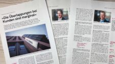 Das Bild zeigt mehrere Seiten eines Zeitungsartikels über die Targobank und OLB. Der Titel lautet 'Die Überlappungen bei Kunden sind marginal'. Es sind Interviews mit den Vorständen Marco Voosen und Berthold Rüsing zu sehen, die über die Zusammenarbeit und die Strategien der Banken sprechen. Der Hintergrund zeigt die Fassade der Targobank mit dem Logo. Der Artikel behandelt Themen wie Corporate Banking, Risikomanagement und die finanzielle Strategie der Banken.