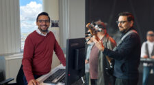 Ein Mann in einem roten Pullover steht an einem Schreibtisch mit einem Lenovo-Computer. Im Hintergrund sieht man ein Fenster mit einer Aussicht auf eine Stadt. Rechts ist ein anderer Mann auf einer Bühne zu sehen, der ein Bassinstrument spielt, während eine Band im Hintergrund auftritt.